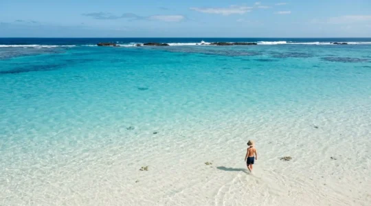 Tranquil turquoise lagoon with crystal-clear shallow water inside protective barrier reef ideal for young children to swim safely