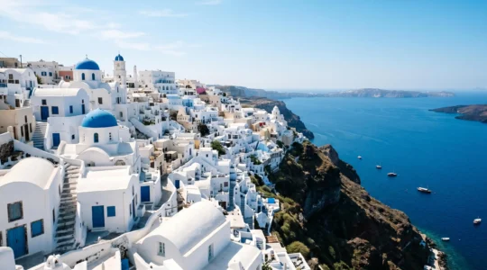 Stunning whitewashed Mediterranean island architecture with blue-domed churches cascading down hillside toward azure sea