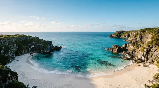 Pristine secluded beach cove with turquoise water and dramatic cliffs, symbolizing the tension between sharing natural beauty and preserving its secrecy
