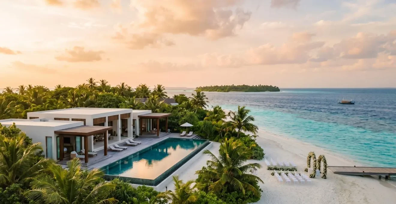 Elegant luxury villa with white architecture overlooking pristine turquoise lagoon, private infinity pool, palm trees, and wedding setup for milestone celebrations