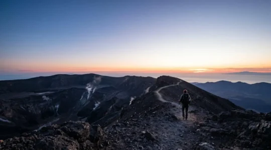 Hikers ascending volcanic crater trail with safety gear on remote island volcano
